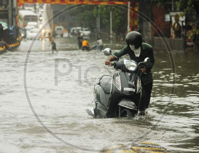 A man walks with his bike on a waterlogged road during rains, in Mumbai, India, July, 2020.
