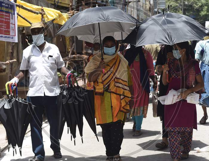 People Hold Umbrellas As They Shop For Flowers At A Market, In Chennai, Monday, July 27, 2020.