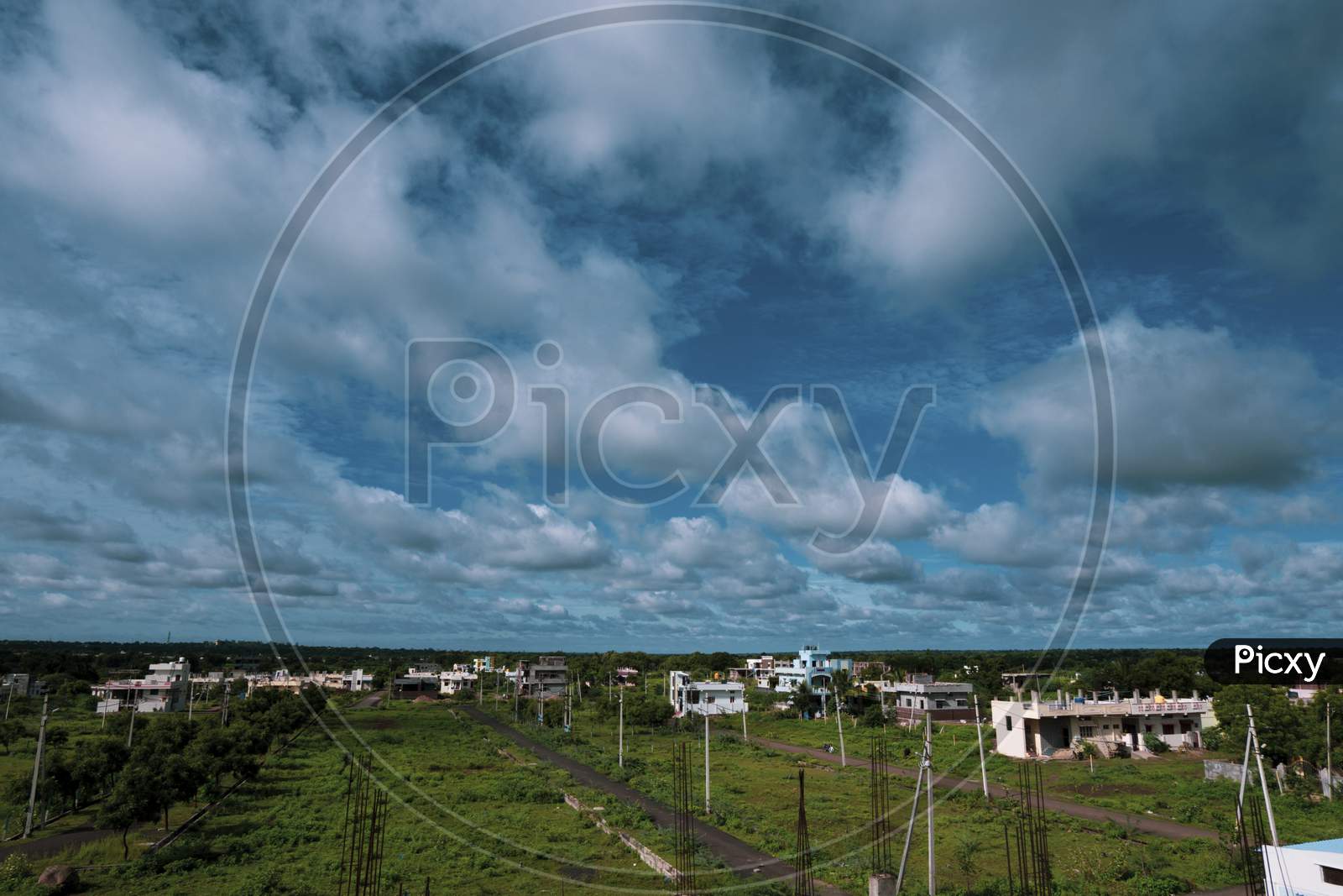 Long View Of City Landscape With Blue Sky, Clouds & Green Land