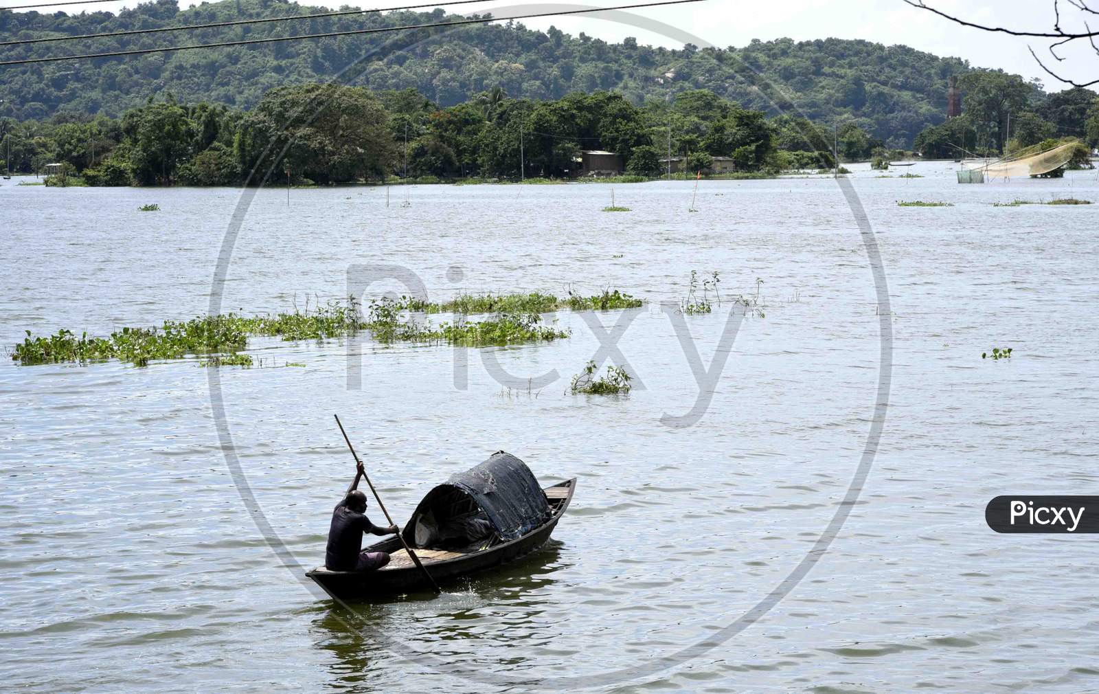 A Fisherman  rows a boat on a flooded area