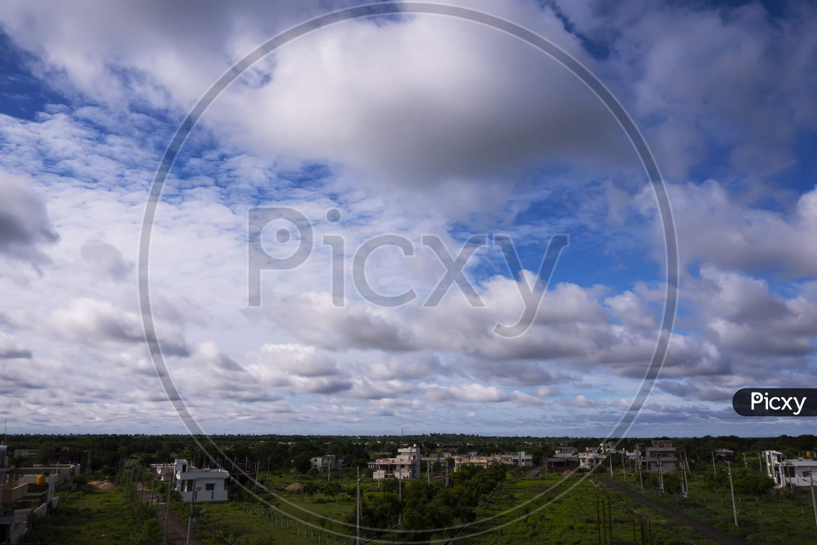Long View Of Cityscape With Blue Sky, Clouds & Green Land