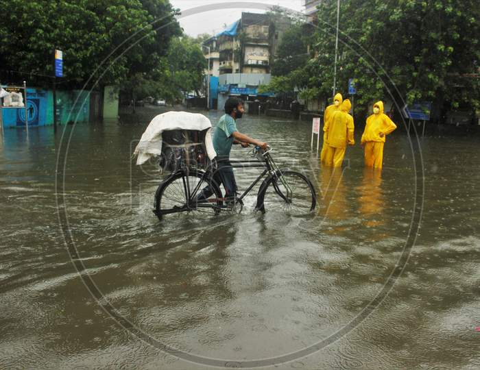 A man walks with his cycle on a waterlogged road during rains, in Mumbai, India, July, 2020.