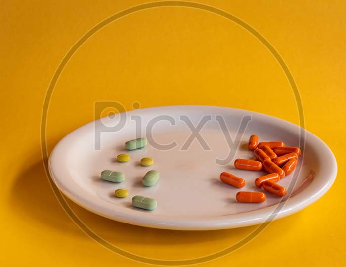 White Plate With Colored Medications On A Orange Background. Pharmaceutical Drug Overdose Concept.
