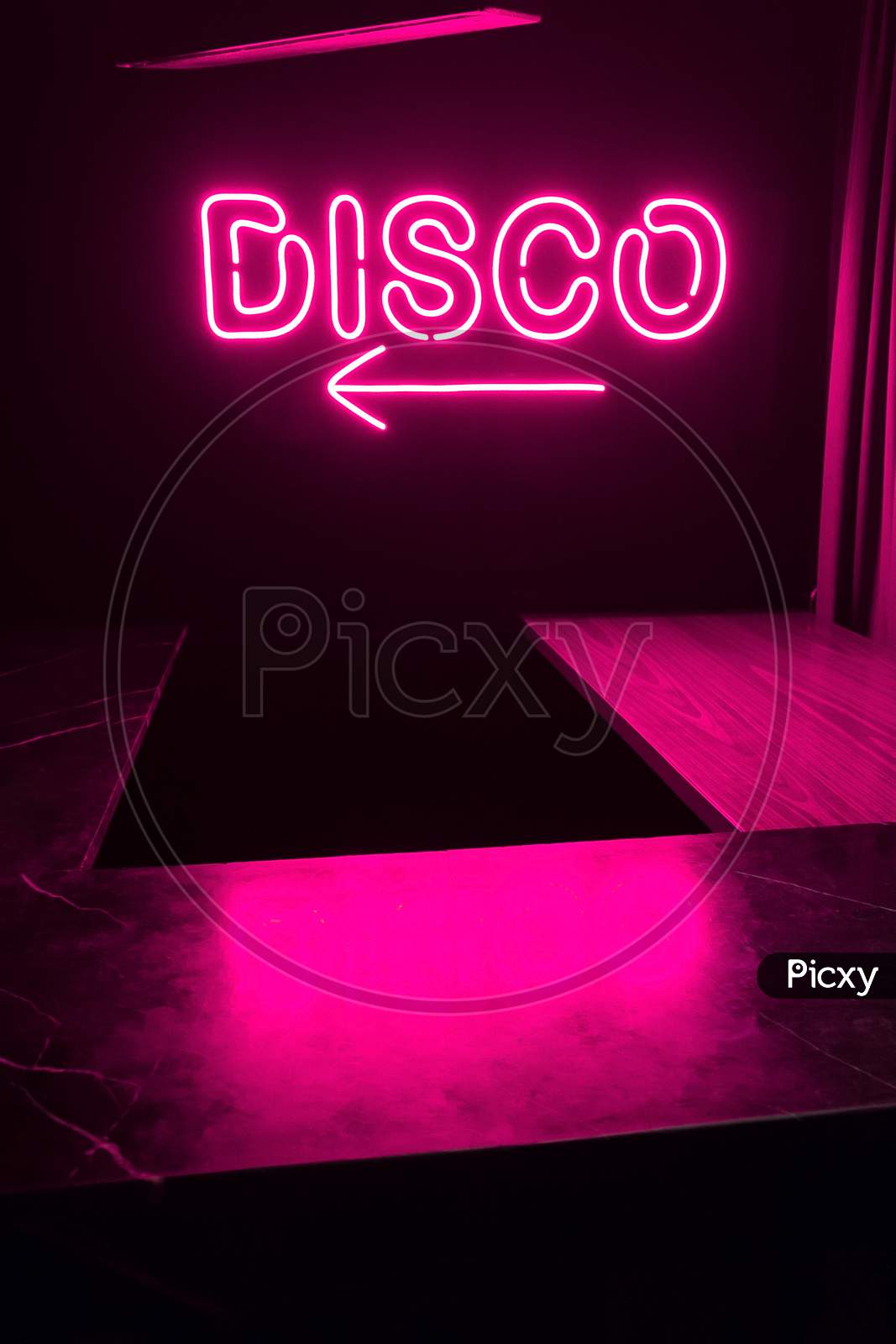 A Bright Glowing Purple Neon Disco Light Word Sign Inside A Night Club.