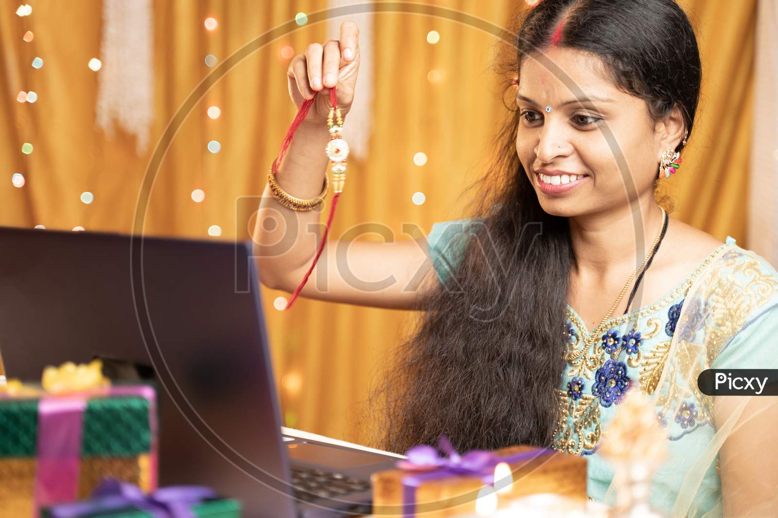 Indian Woman In Tradition Dress On Video Call Or Chat At Raksha Bandhan Festival Telling Her Brother To Tie Rakhi - Concept Of Distance Relations, Festival Celebrations And Technological Lifestyle