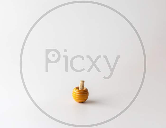 A small wooden top with earthy yellow color against white background with copy space