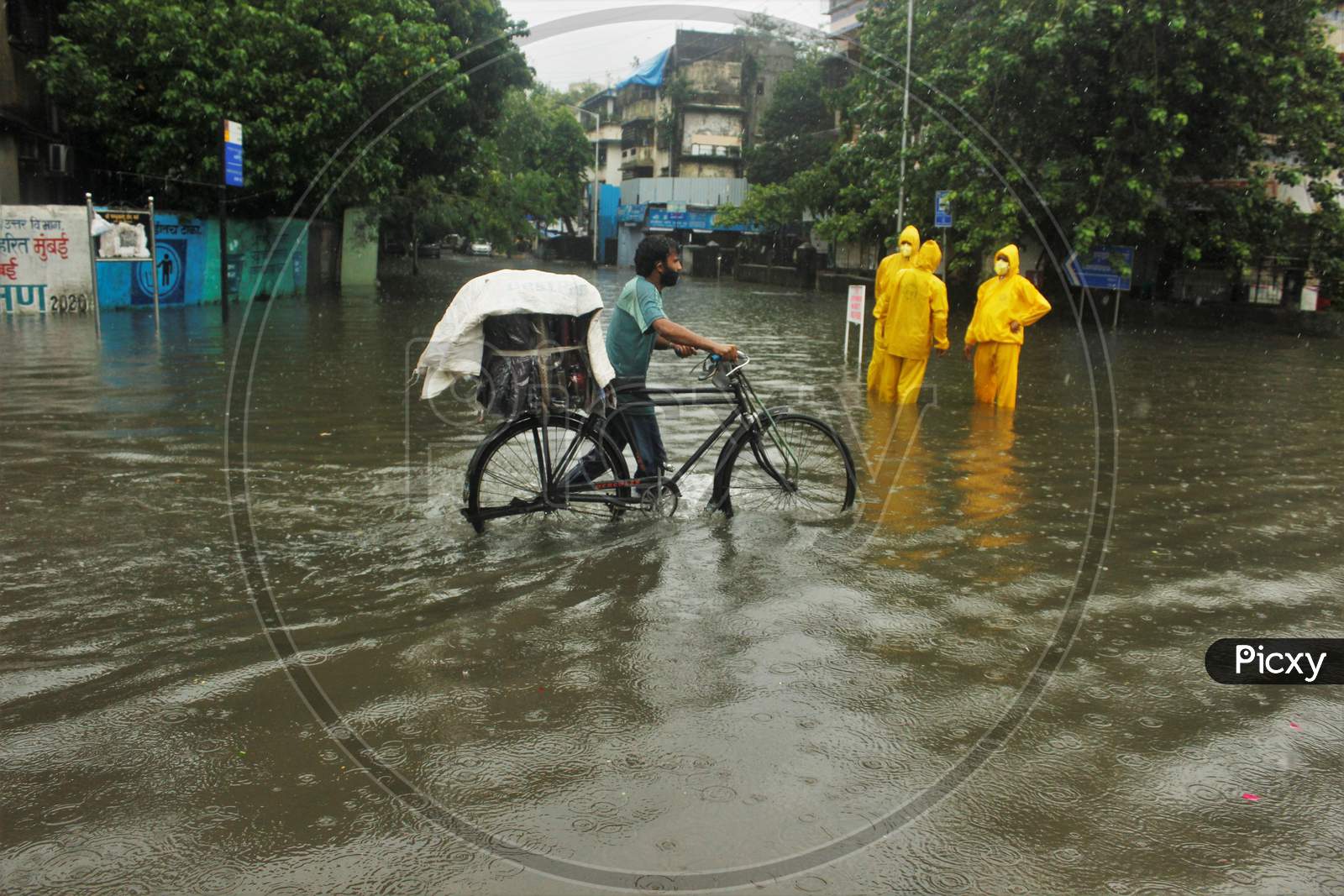 A man walks with his cycle on a waterlogged road during rains, in Mumbai, India, July, 2020.