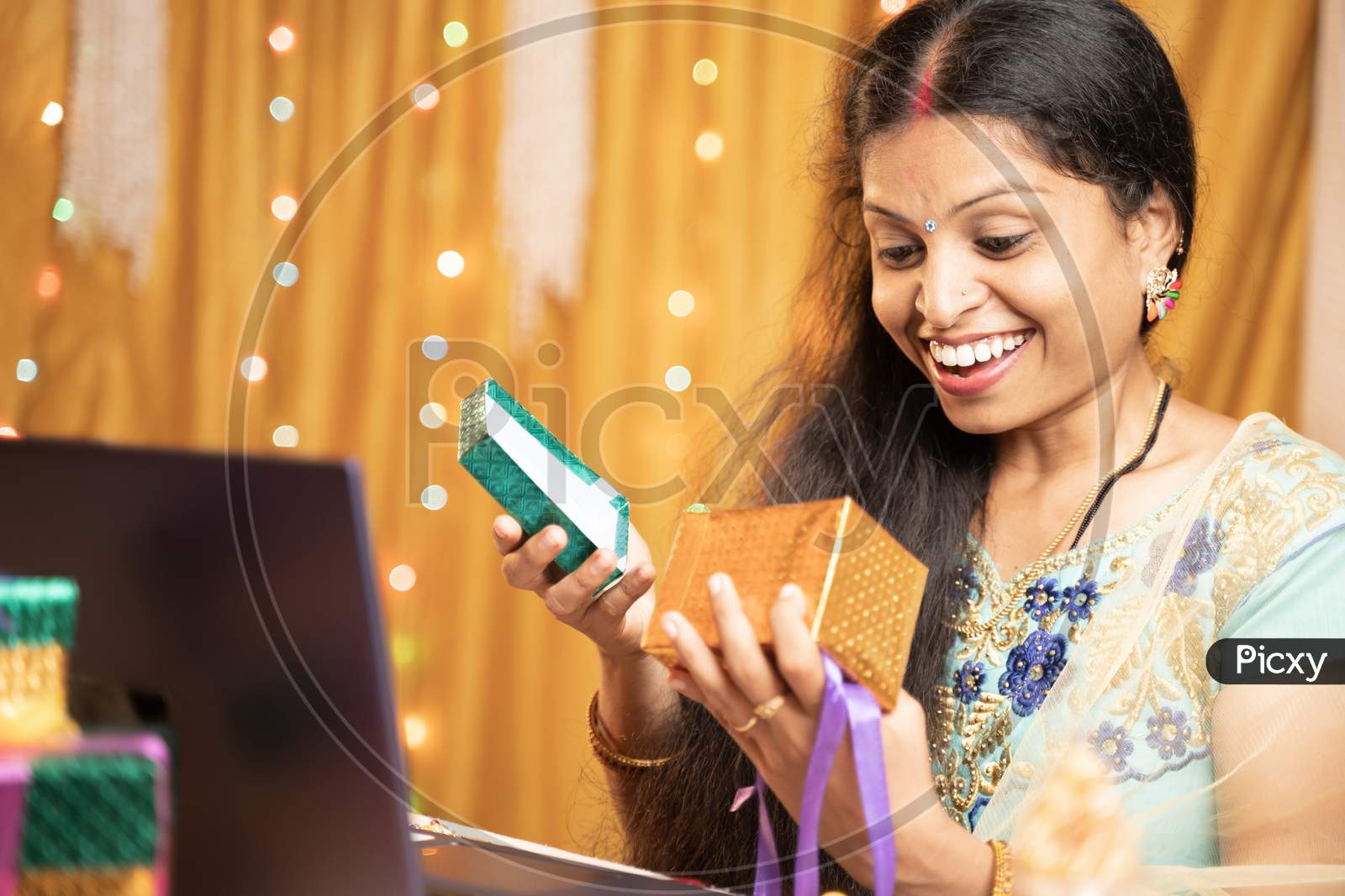 Happy Excited Woman Opening Gift In front Of Laptop During Video Call Or Chat At Raksha Bandhan Festival Ceremony - Concept Of Distance Relations, Celebrations And Lifestyle.