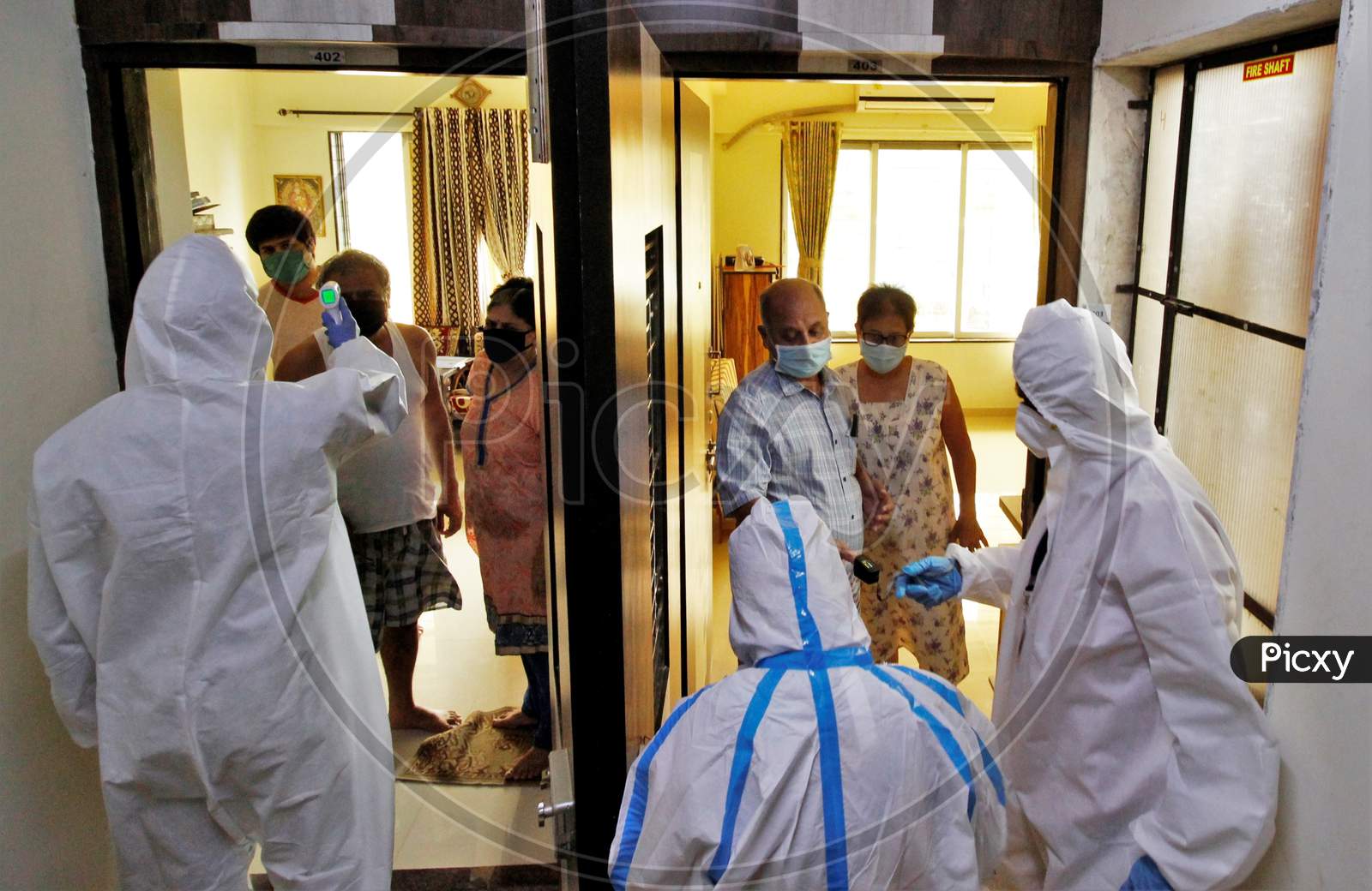 Healthcare workers wearing personal protective equipment (PPE) check the temperature and measure pulse of a residents during a check-up campaign for the coronavirus disease (COVID-19), in Mumbai, India on July 26, 2020.