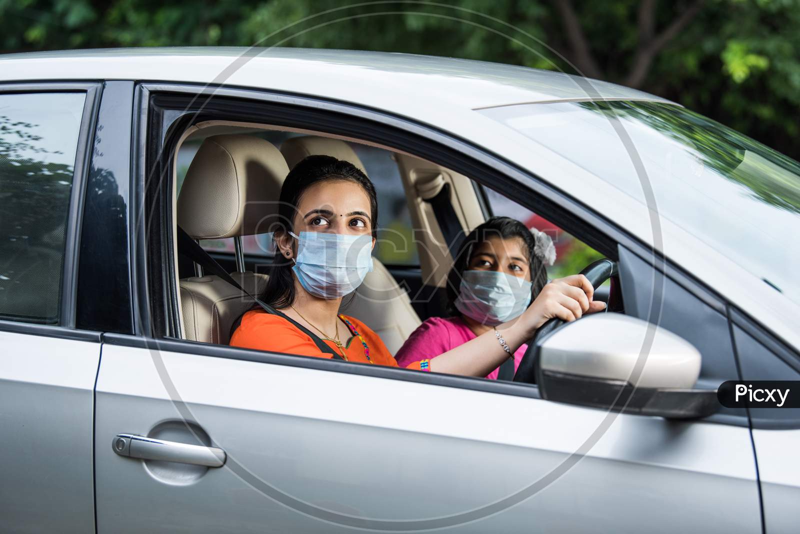 Indian Young Mother And Daughter Wearing Face Mask While Driving Car