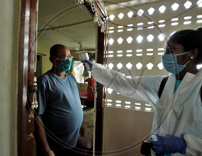 A healthcare worker wearing personal protective equipment (PPE) checks the temperature of a resident during a check-up campaign for the coronavirus disease (COVID-19), in Mumbai, India on July 26, 2020.