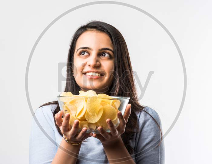 Indian / Asian Pretty Young Girl Eating Potato Chips On White Background With Copyspace