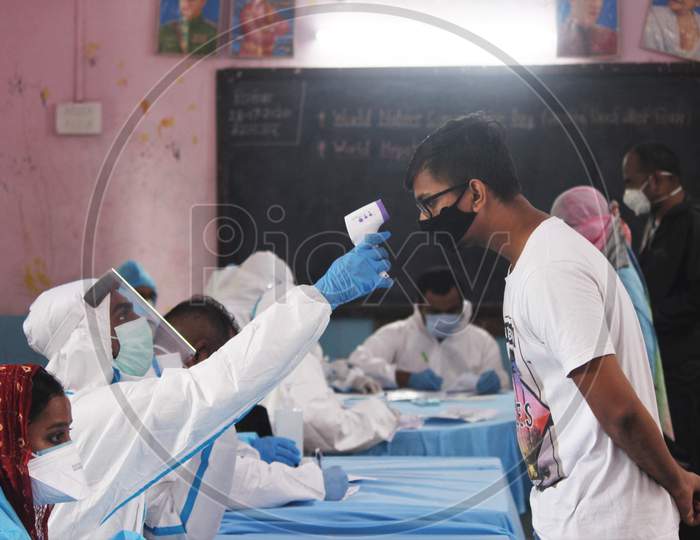 A healthcare worker wearing personal protective equipment (PPE) checks the temperature of a boy during a check-up campaign for the coronavirus disease (COVID-19), in Mumbai, India on July 28, 2020.
