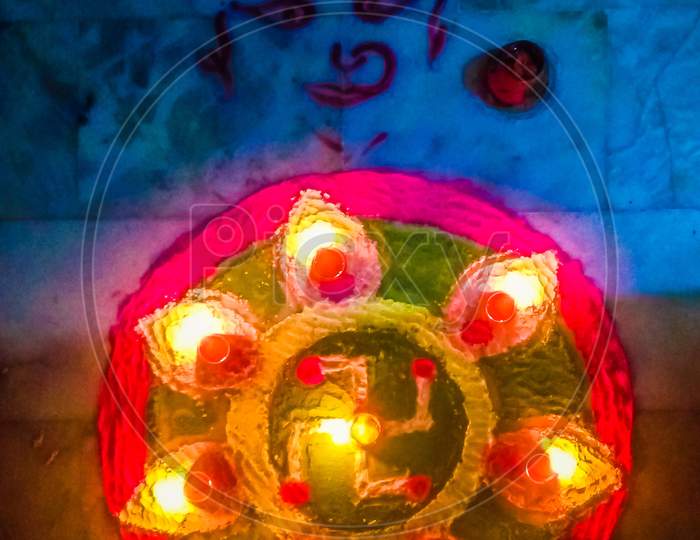 Rangoli with colours and earthen lamps on Diwali celebration along with Laxmi mata symbol drawn sidewise.