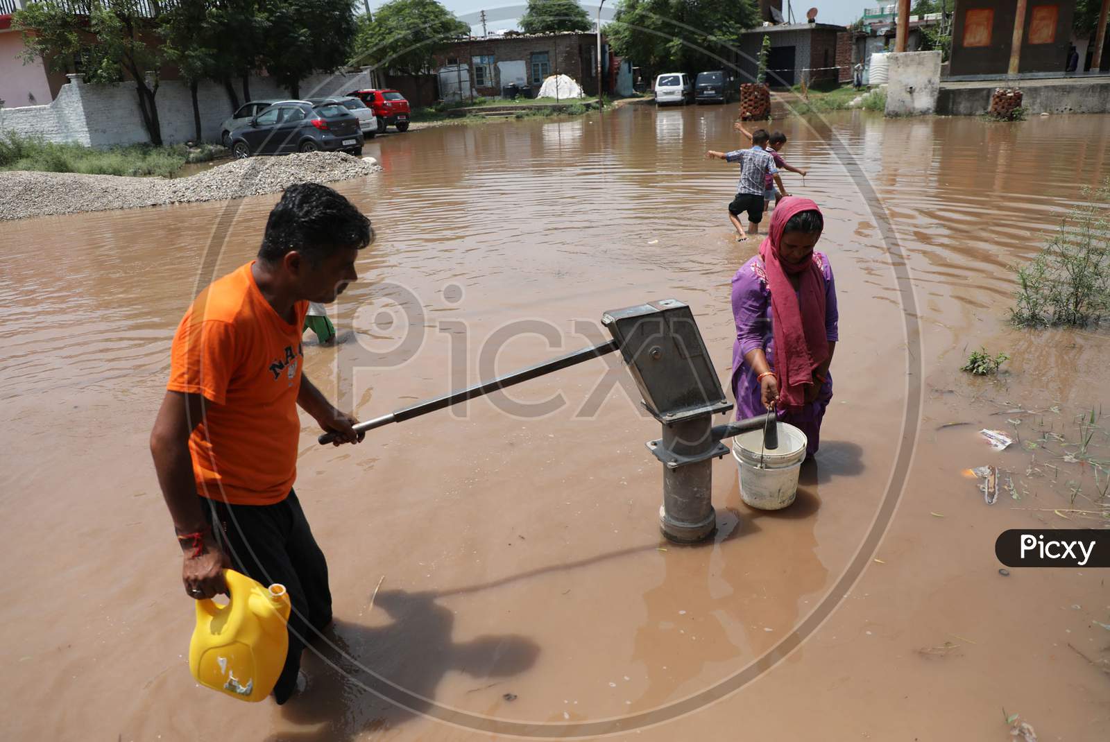 A Woman collects drinking water from a hand pump at a flooded street following monsoon rains on the outskirts in Jammu on July 29, 2020.