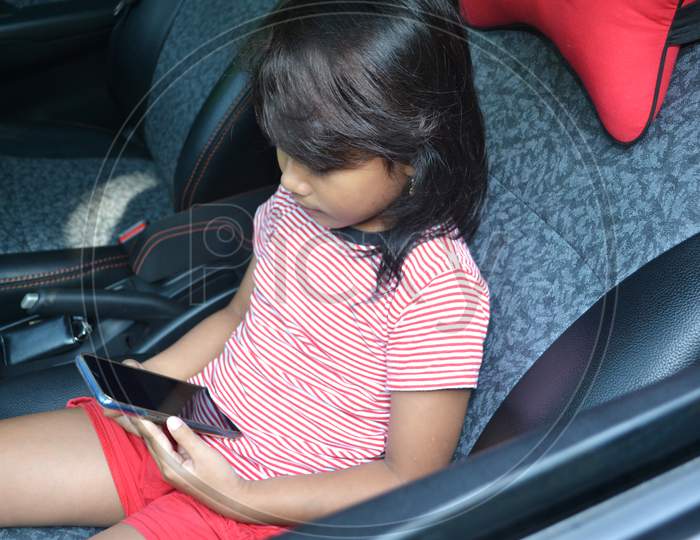 Little Girl Playing A Cellphone In The Car