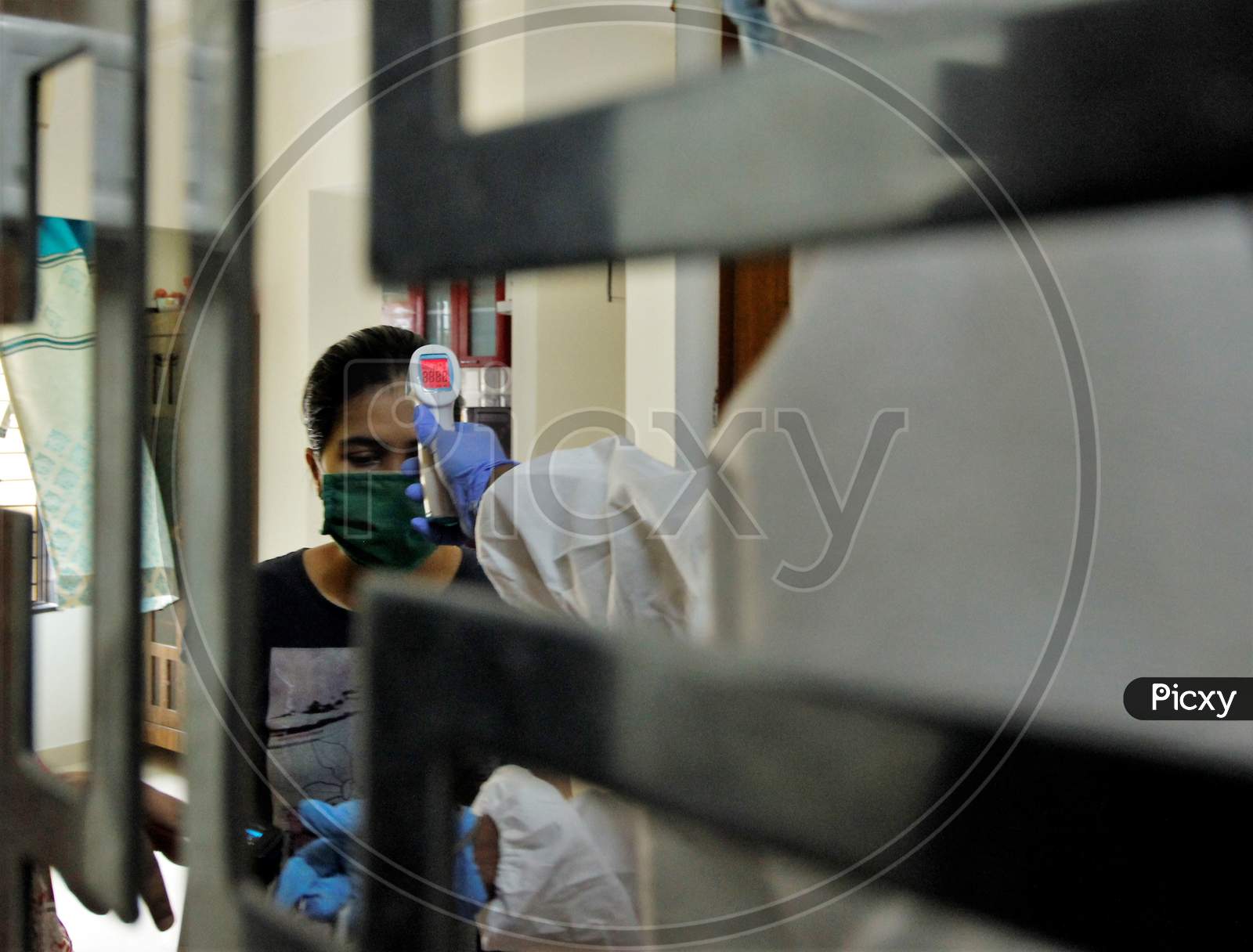 A healthcare worker wearing personal protective equipment (PPE) checks the temperature of a resident during a check-up campaign for the coronavirus disease (COVID-19), in Mumbai, India on July 26, 2020.
