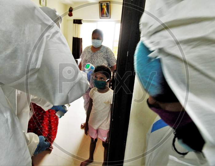 A healthcare worker wearing personal protective equipment (PPE) checks the temperature of a girl during a check-up campaign for the coronavirus disease (COVID-19), in Mumbai, India on July 26, 2020.