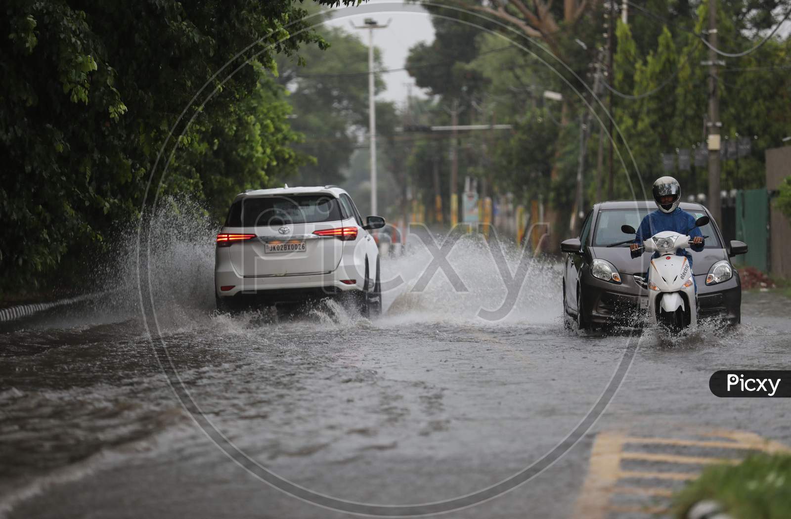 People drive through a street during rains on the outskirts of Jammu on July 29, 2020.