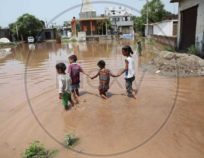 Children walk on a flooded street following monsoon rains on the outskirts of Jammu on July 29, 2020.