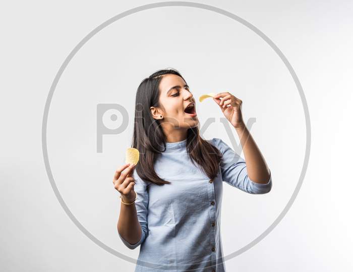 Indian / Asian Pretty Young Girl Eating Potato Chips On White Background With Copyspace