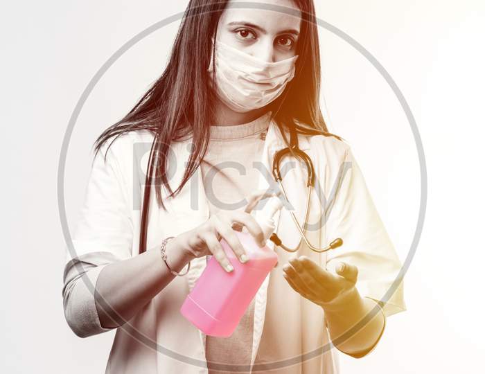 Indian Female Doctor In Uniform And Face Mask Using Sanitizer Or Disinfectant Spray
