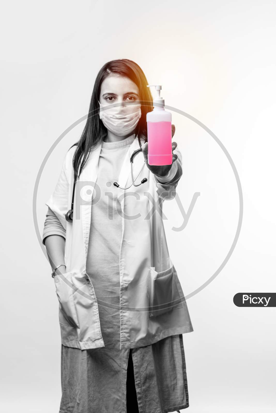 Indian Female Doctor In Uniform And Face Mask Using Sanitizer Or Disinfectant Spray