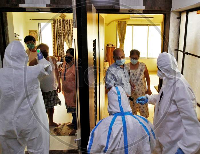 Healthcare workers wearing personal protective equipment (PPE) check the temperature and measure pulse of a residents during a check-up campaign for the coronavirus disease (COVID-19), in Mumbai, India on July 26, 2020.