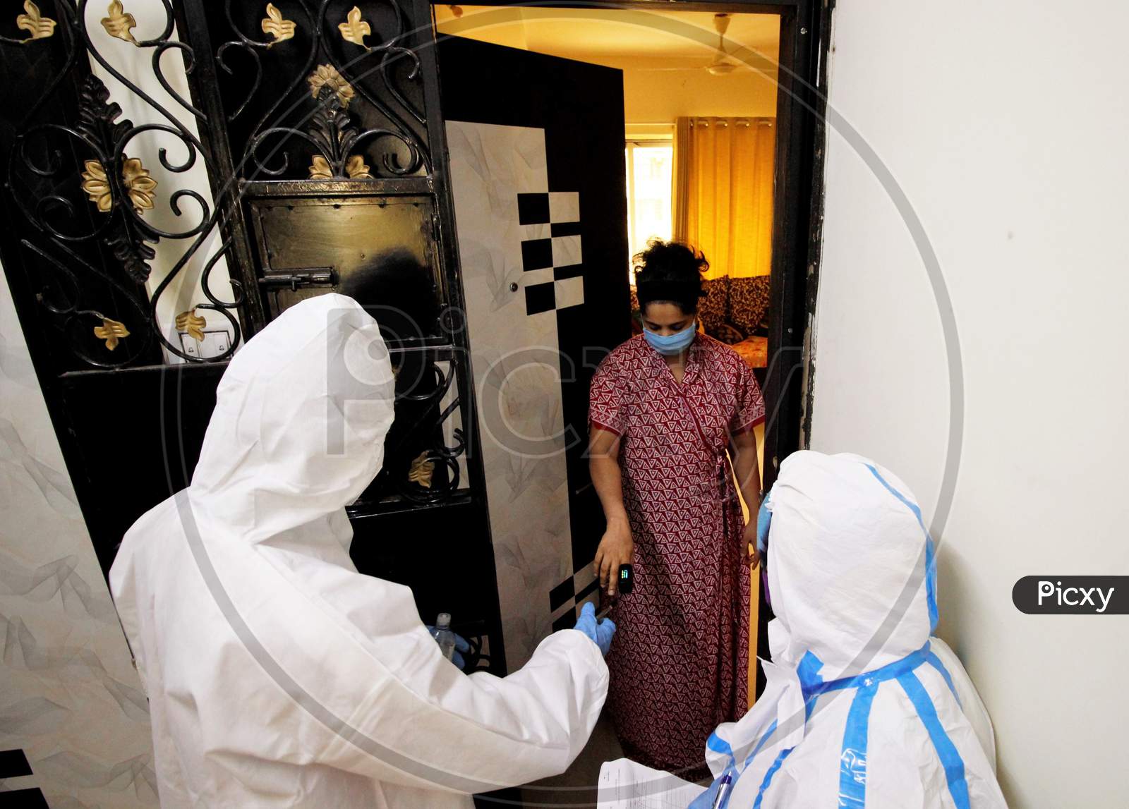 Healthcare workers wearing personal protective equipment (PPE) measure the pulse of a resident during a check-up campaign for the coronavirus disease (COVID-19), in Mumbai, India on July 26, 2020.