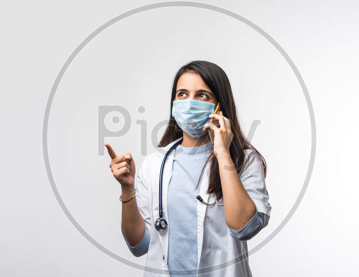 Indian Female Doctor With Stethoscope Wearing Protective Mask In Pandemic Talking On Smartphone