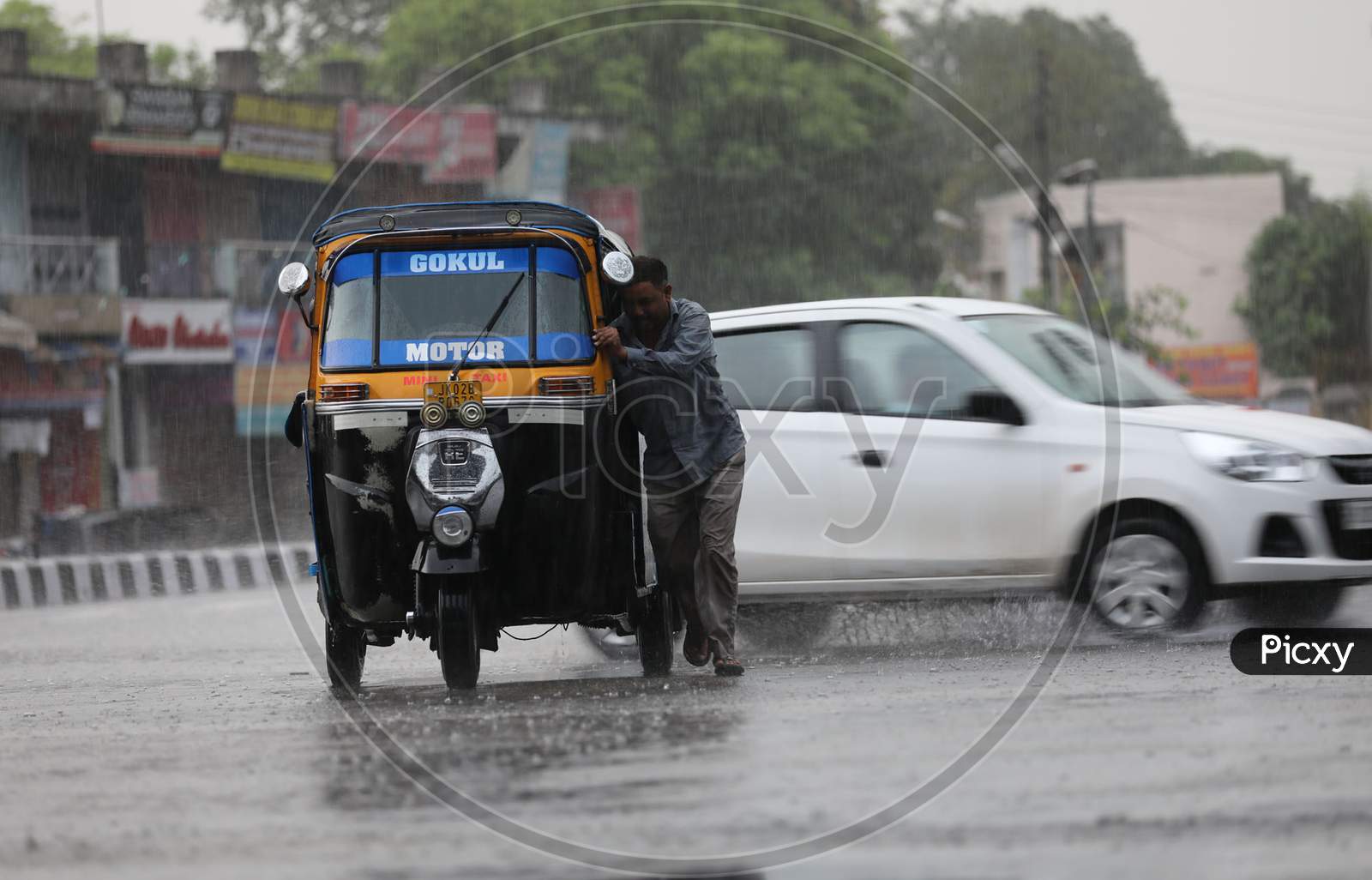 A man pushes an auto rickshaw through a flooded street during a monsoon shower in Jammu on July 29, 2020.
