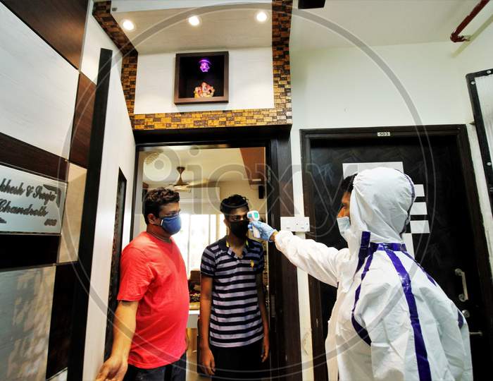 A healthcare worker wearing personal protective equipment (PPE) checks the temperature of residents during a check-up campaign for the coronavirus disease (COVID-19), in Mumbai, India on July 26, 2020.