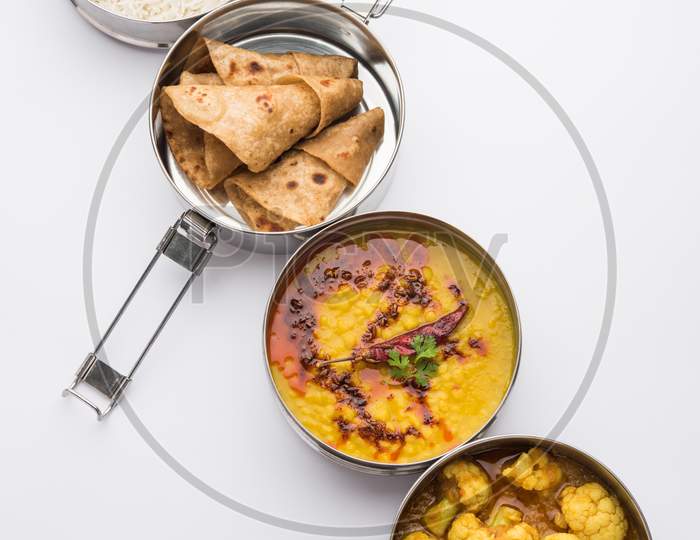 Indian Lunchbox Or Tiffin Includes Cauliflower Masala, Dal Fry, Rice, Chapati And Salad