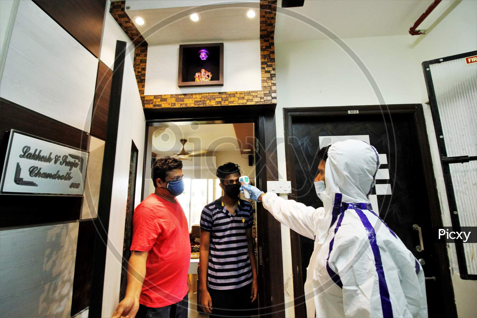 A healthcare worker wearing personal protective equipment (PPE) checks the temperature of residents during a check-up campaign for the coronavirus disease (COVID-19), in Mumbai, India on July 26, 2020.