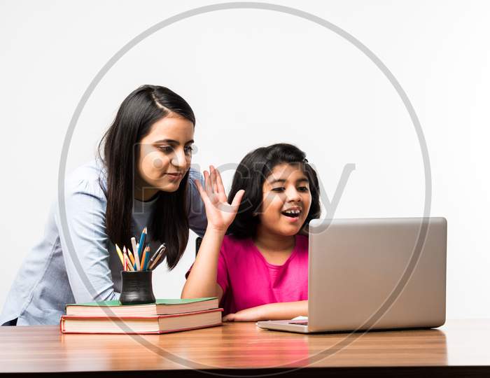 Indian / Asian Little Girl Studying Using Her Laptop Or Attending Online School At Home With Mother