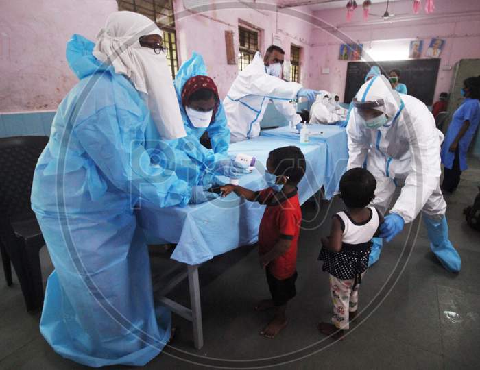 A Health worker in personal protective equipment (PPE) check the temperature and measures the pulse of a kid during a check up campaign for the coronavirus disease (COVID-19),  at a children's home , in Mumbai, India July 28, 2020.