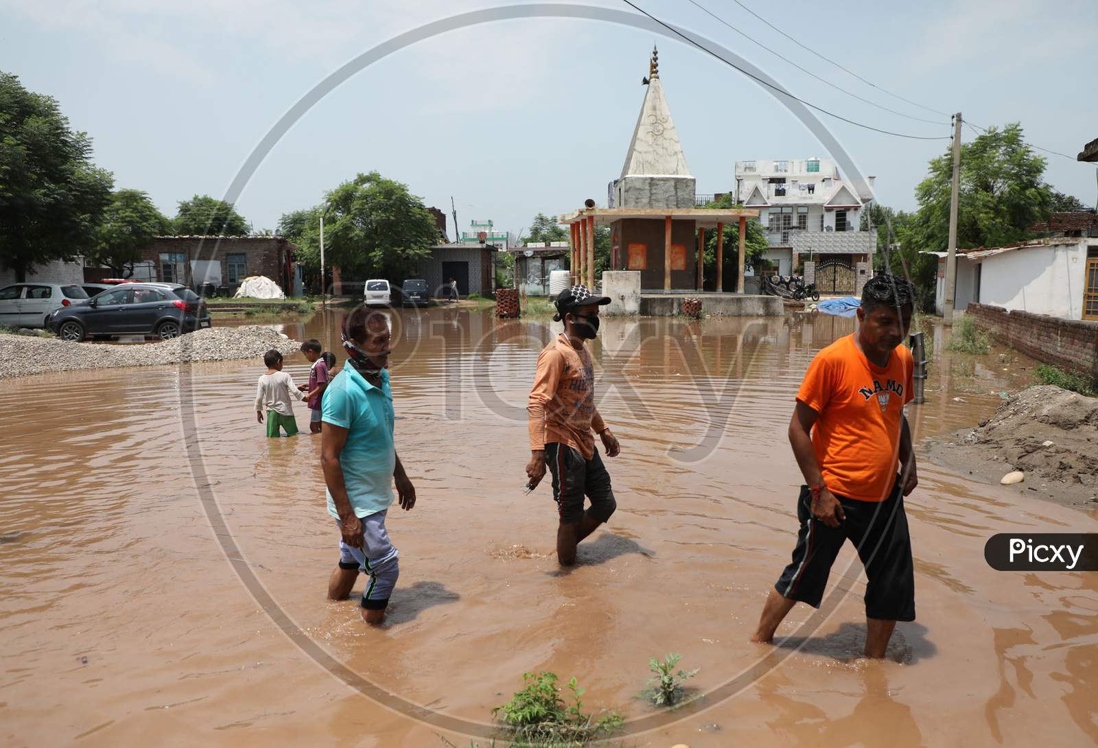 People walk on a flooded street following monsoon rains on the outskirts of Jammu on July 29, 2020.