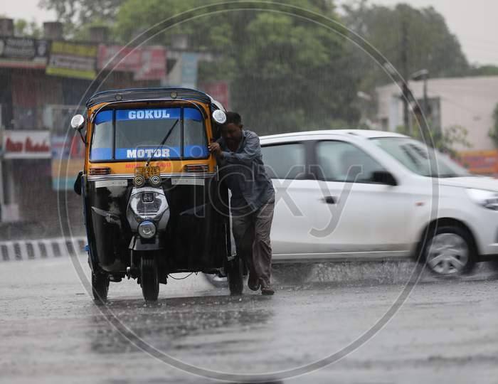 A man pushes an auto rickshaw through a flooded street during a monsoon shower in Jammu on July 29, 2020.