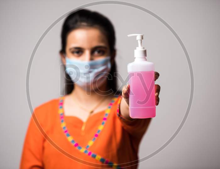 Beautiful Indian Girl Holds Sanitizer On Outstretched Arm, Focus On Bottle. Corona Virus Concept