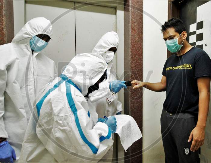 Healthcare workers wearing personal protective equipment (PPE) measure the pulse of a resident during a check-up campaign for the coronavirus disease (COVID-19), in Mumbai, India on July 26, 2020.