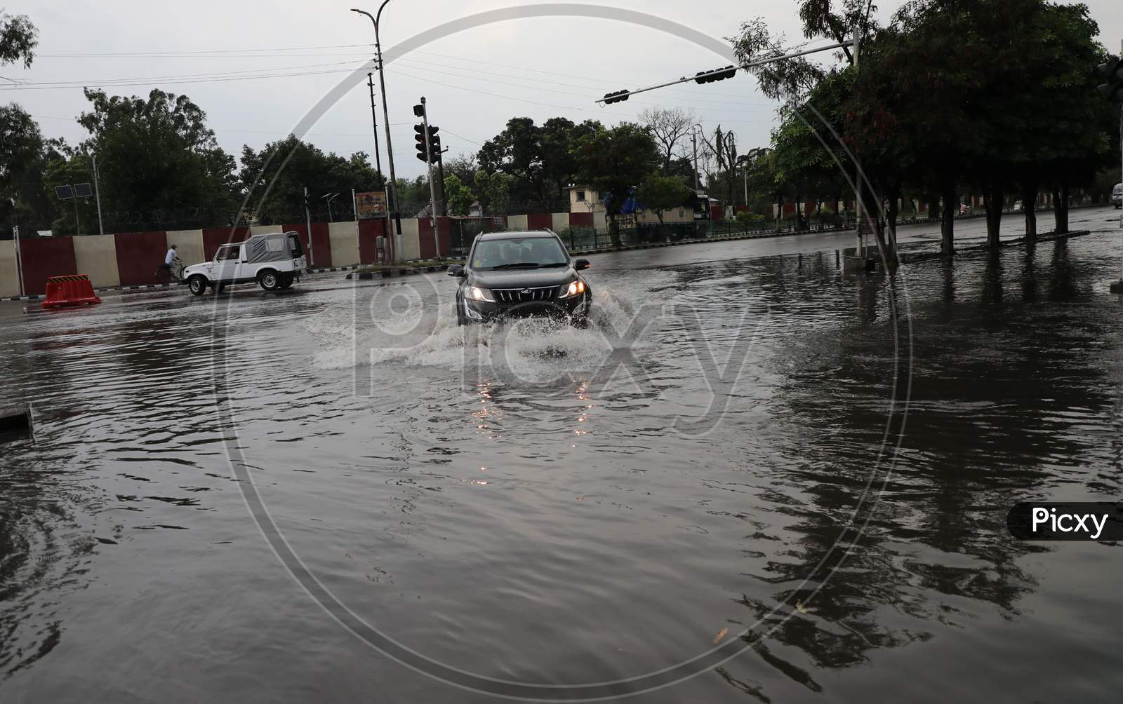 People drive through a water-logged street during rains on the outskirts of Jammu on July 29, 2020.