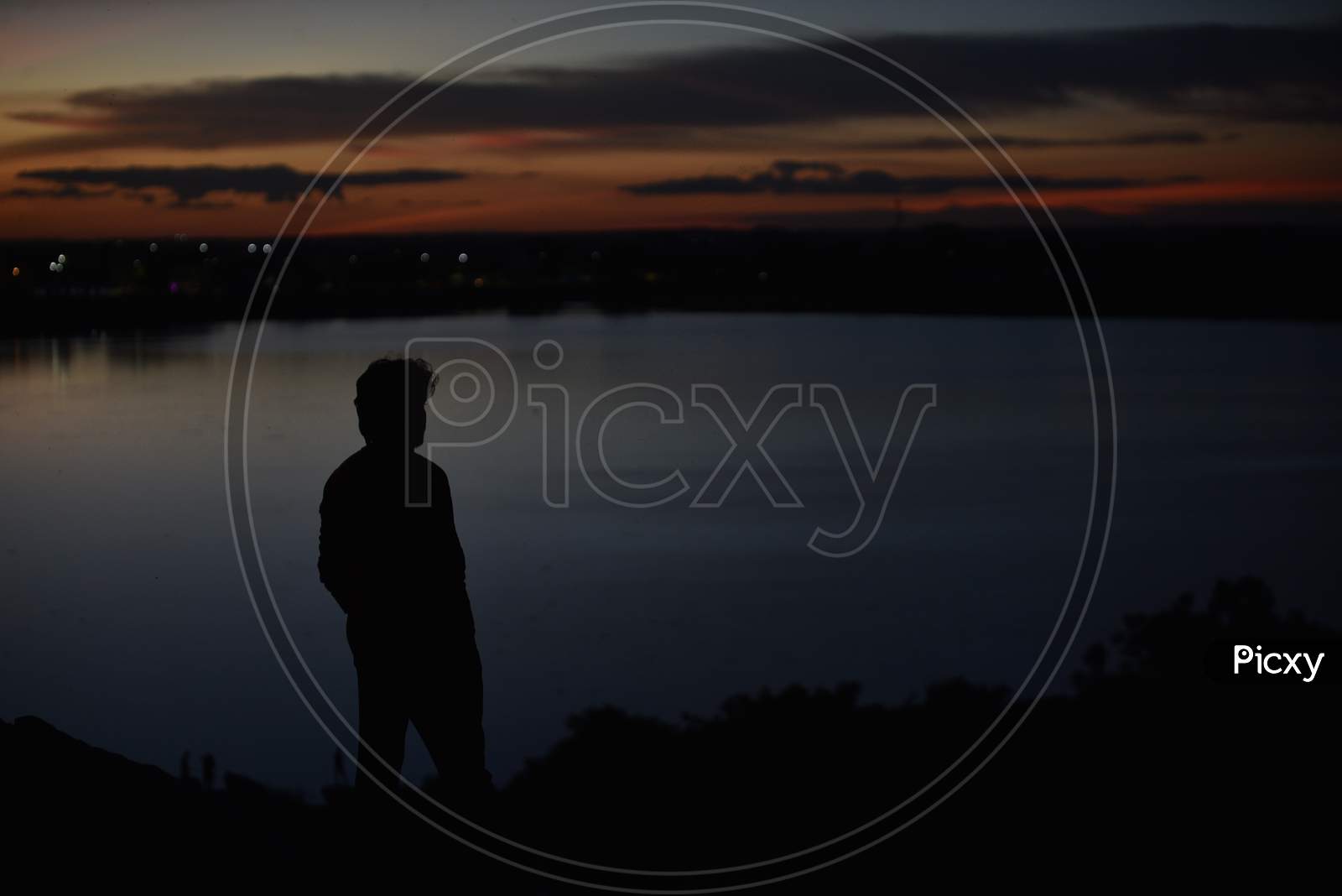 Silhouette of a young man standing by the lake