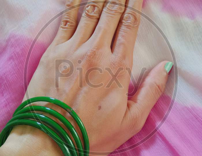 Woman's hand with green bangels.