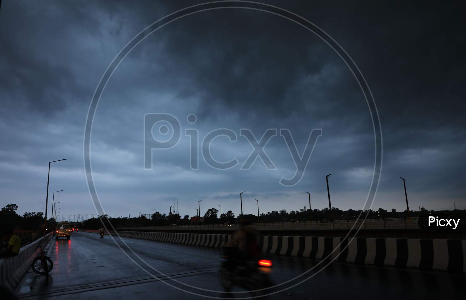 People drive through a street as an overcast sky is seen on the outskirts of Jammu on July 29, 2020.