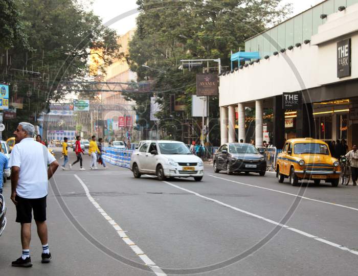 High road, crowd and road side parking partial view, at Park street, Kolkata.