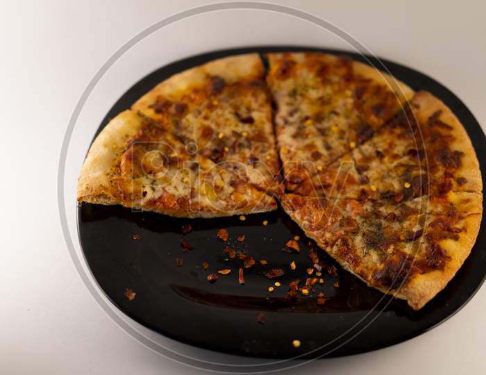 Pizza on a black plate against a white  background .