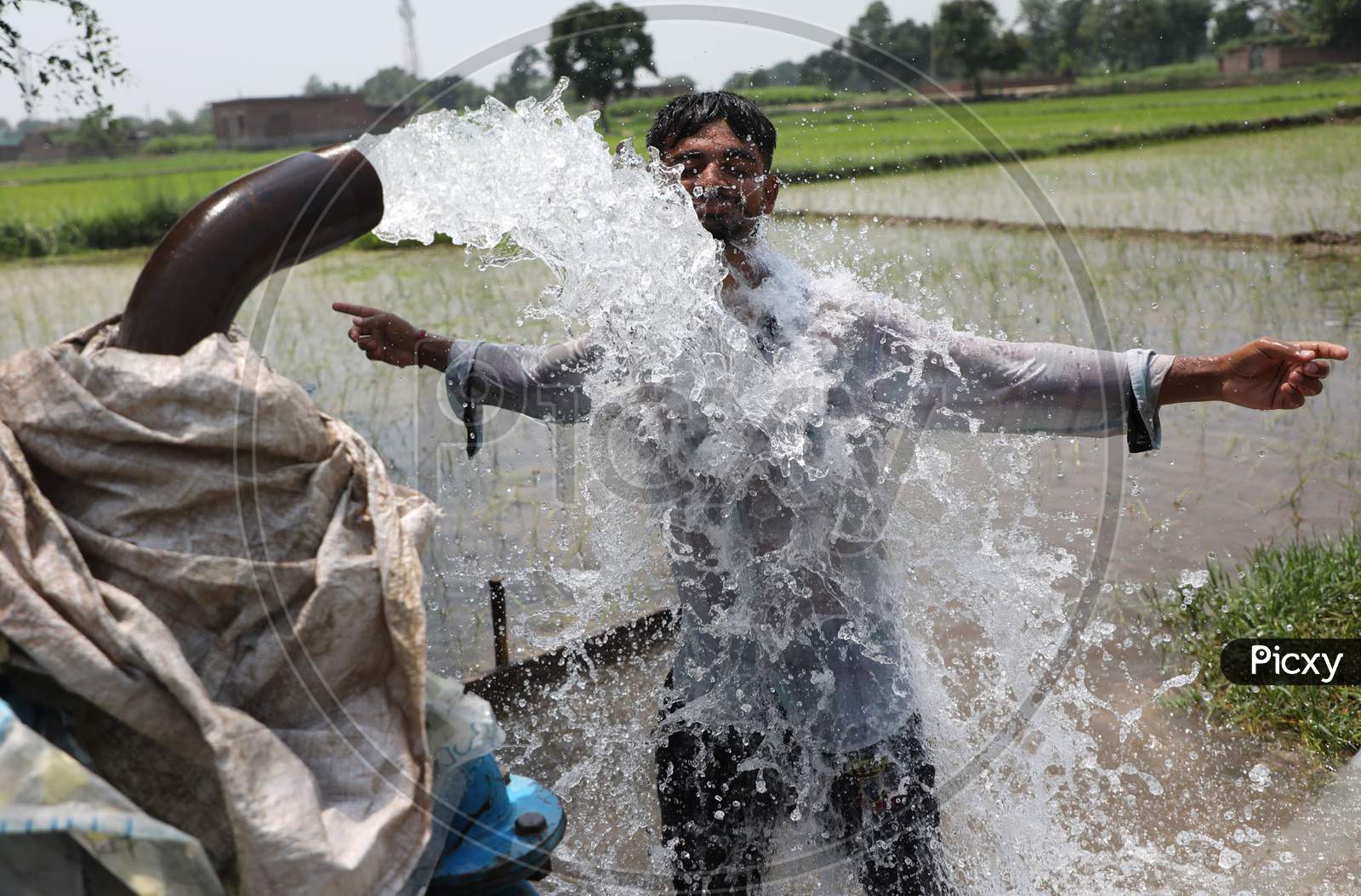 A young man enjoys the cool splash from a tube well on a hot summer day during Unlock 2.0 in Jammu on July 03, 2020.