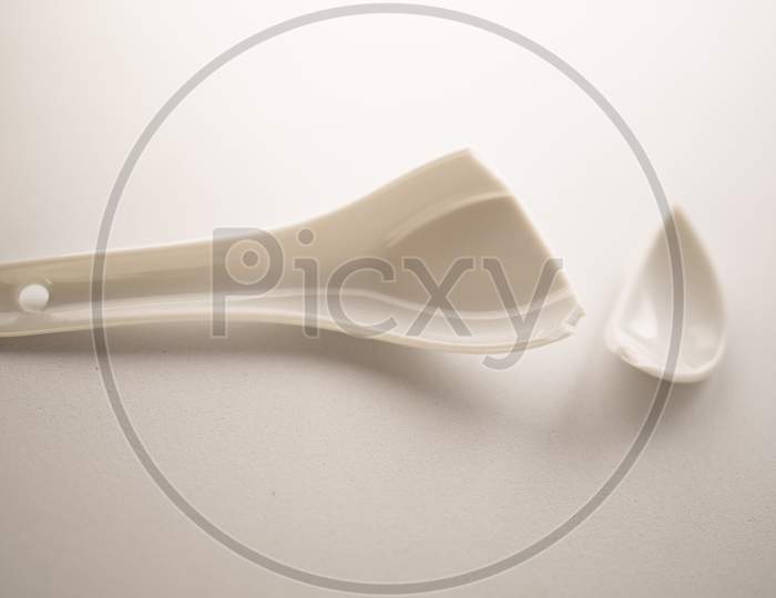 Broken white ceramic spoon on a white background