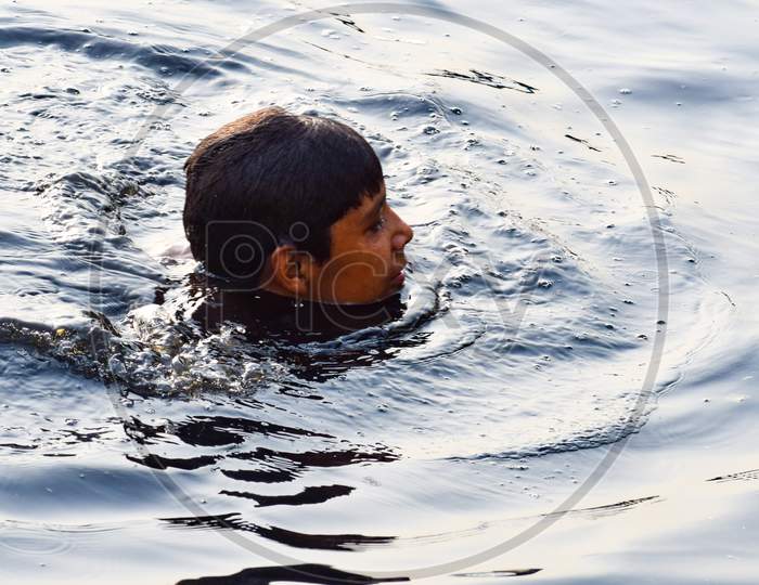 Delhi, India - Dec 31, 2019 : Man taking bath in holy river of Yamuna during morning time in Delhi India, People taking holy dip inside Yamuna river