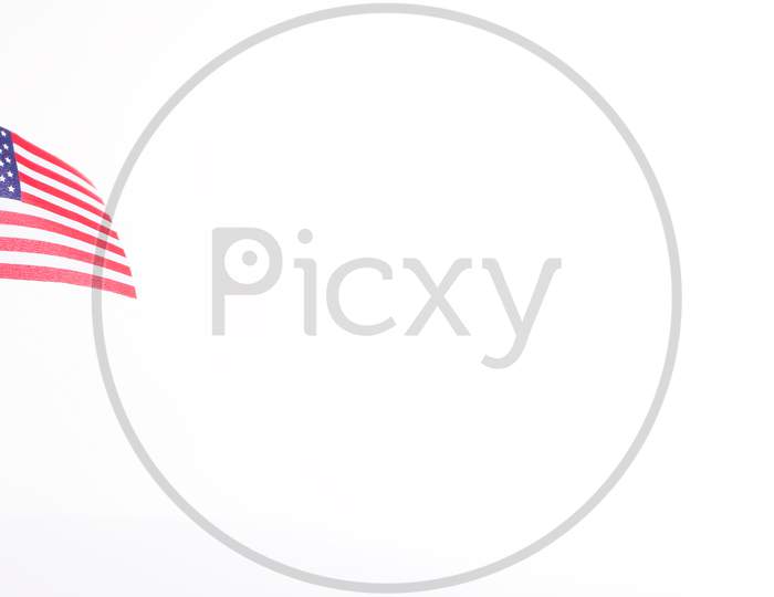 The American Flag Draped On A Flag Stand. American Independence Day .National Emblem. Patriotic Image On White Background. Us Independence Day